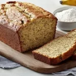 Loaf of easy moist banana bread on a wooden board with sliced pieces.